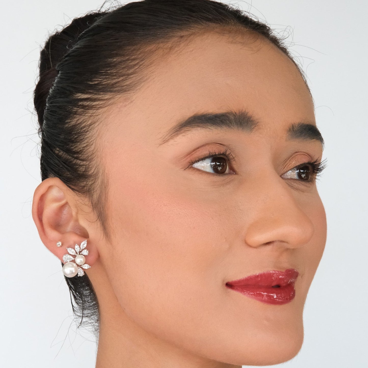 Woman wearing a floral earring on a plain background