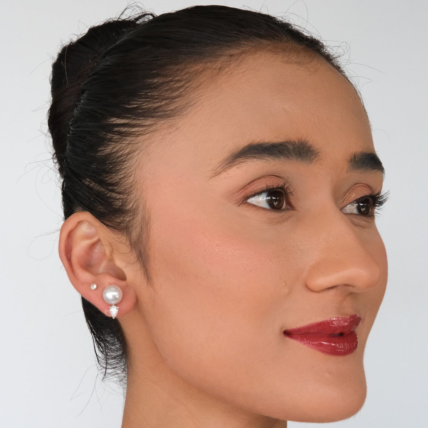 Woman wearing pearl earrings against a plain background