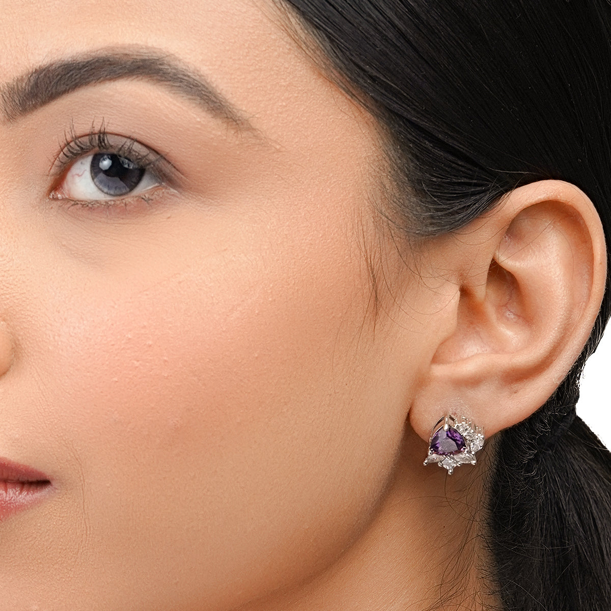Close-up of model wearing purple stud earring with white CZ stones