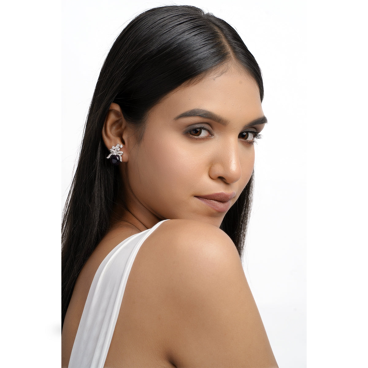 Side view of model with bow-shaped purple stud earrings