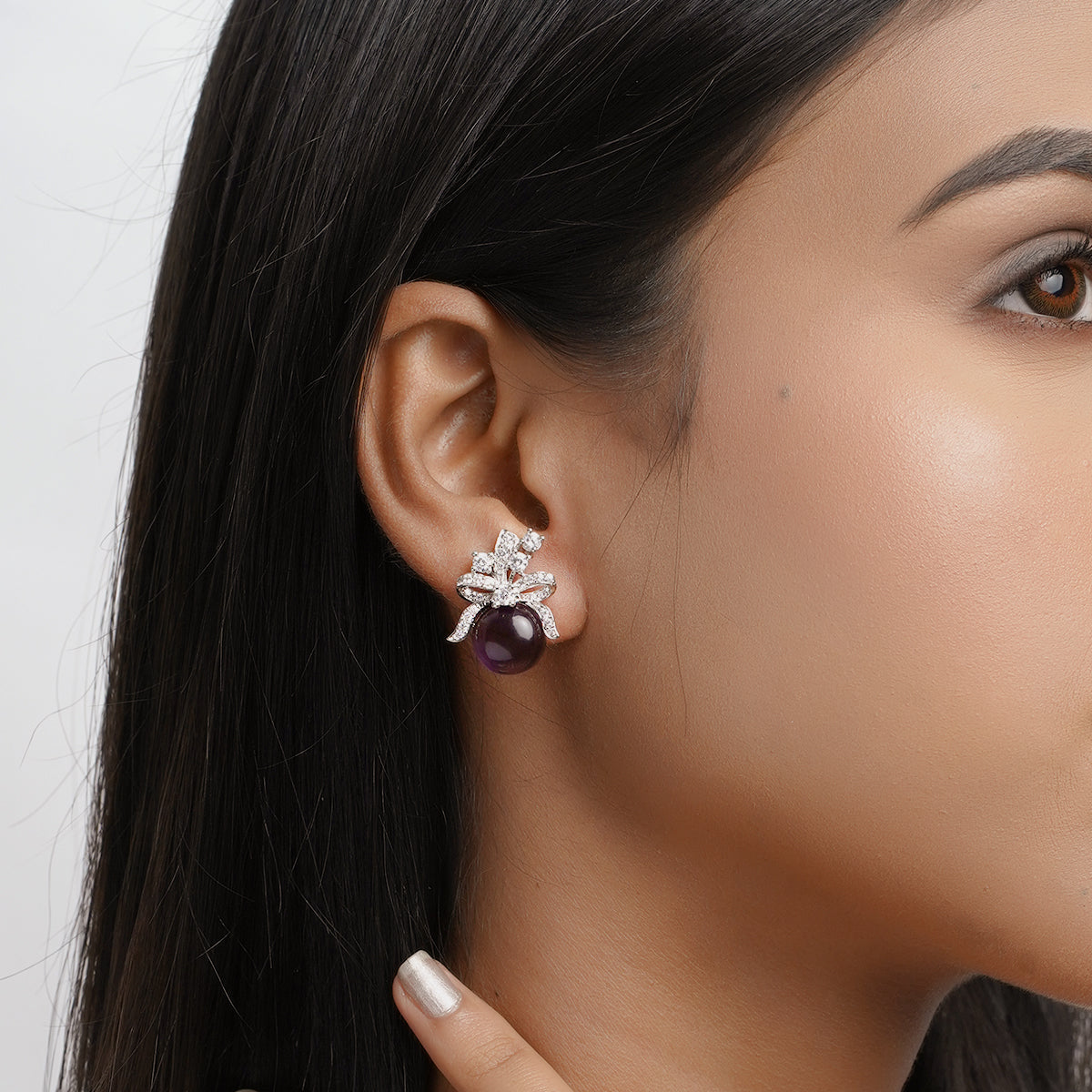 Close-up of woman wearing purple amethyst earrings with bow design