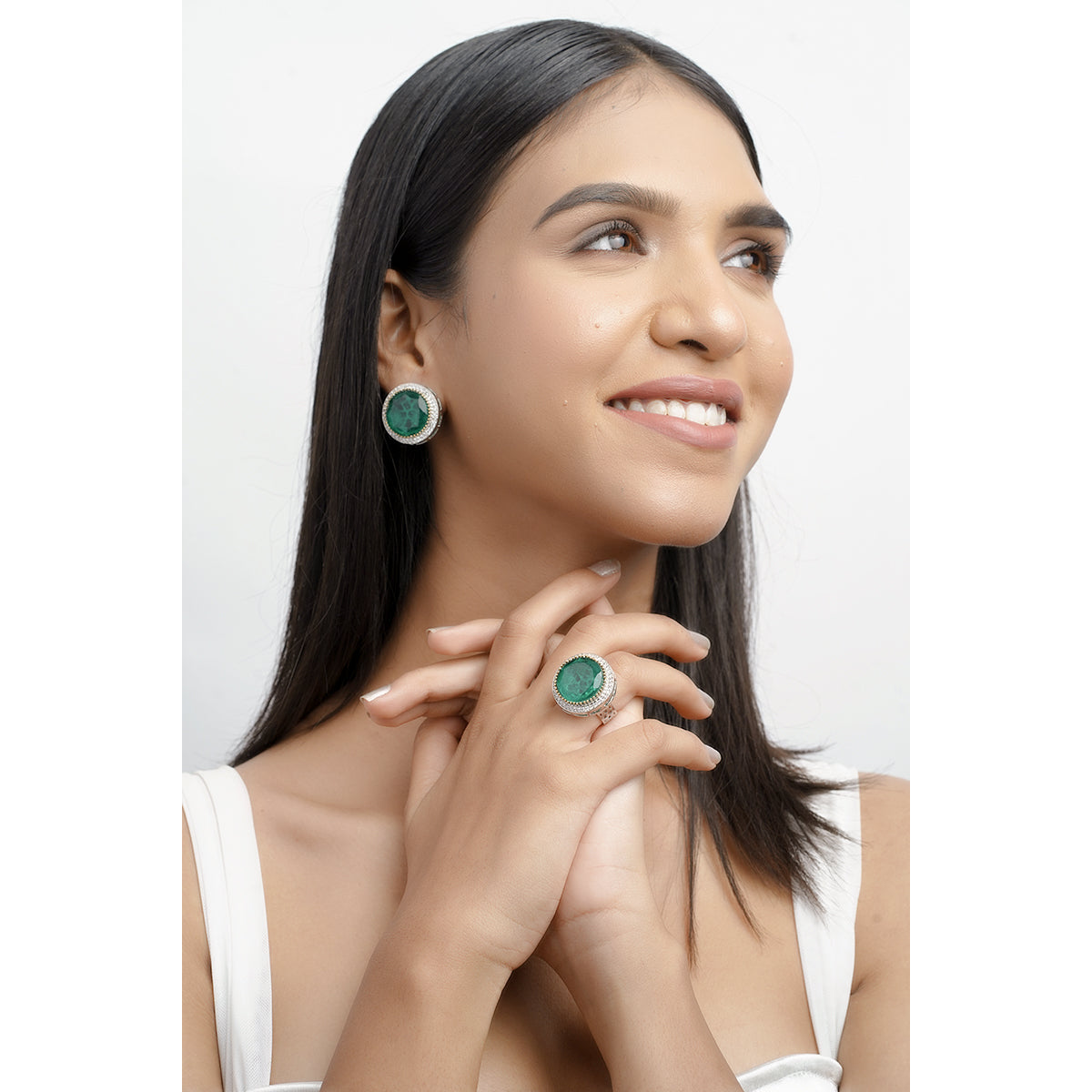 Model smiling while wearing green cocktail ring with matching earrings