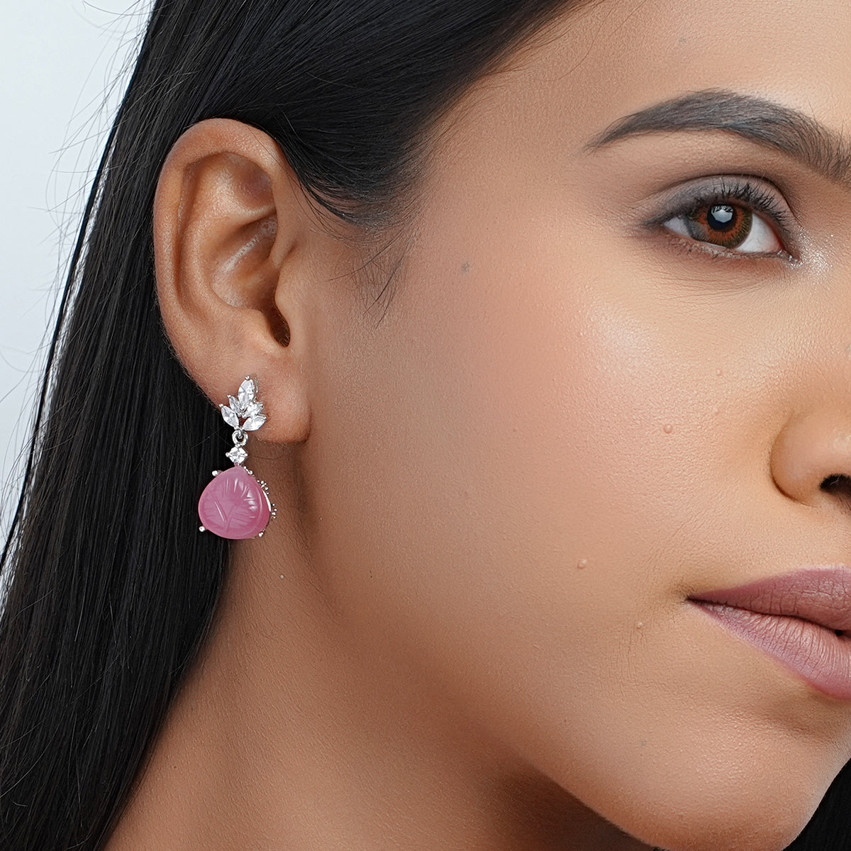 Model wearing pink dangle earrings with carved stone drops