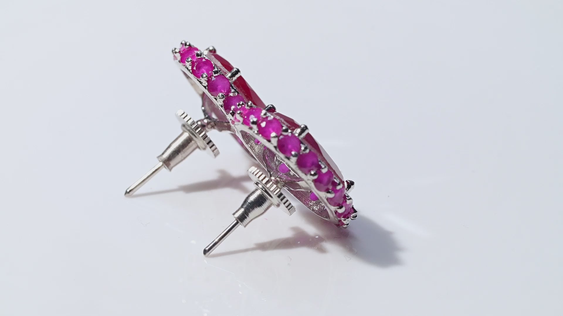 Video of pink ruby stud earrings rotating on white surface