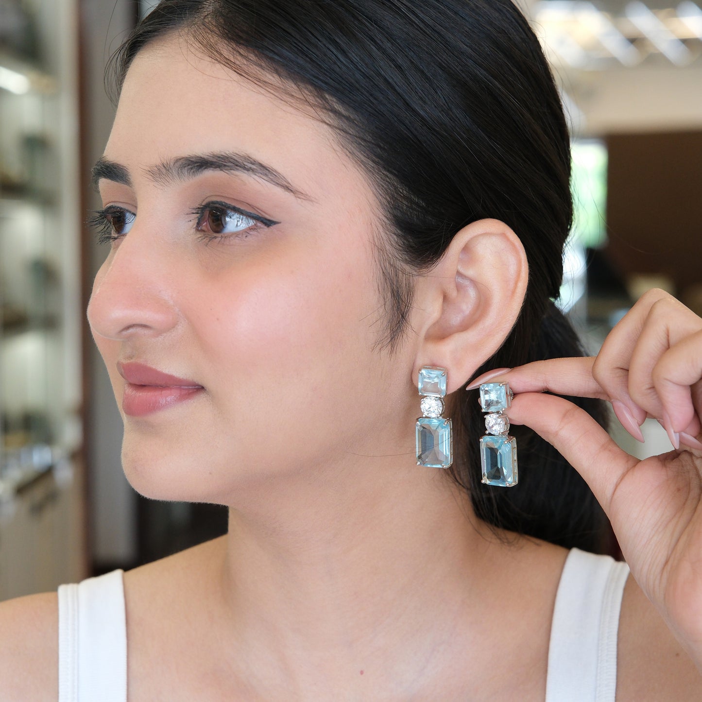 Model wearing Sky Blue Geometric Drop Earrings in a side view, highlighting the elegant geometric drop design and sparkling sky blue stones.