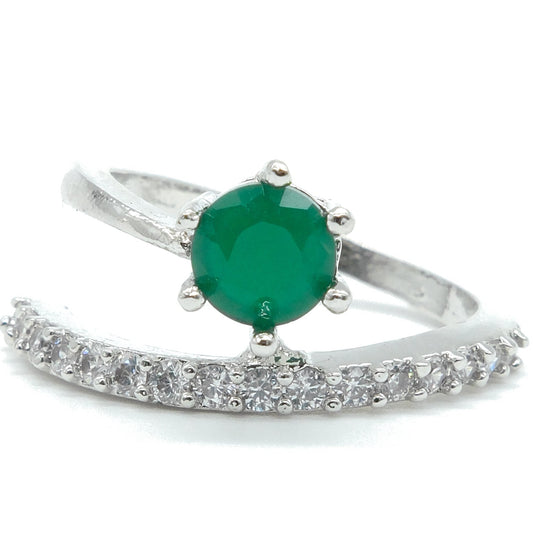A silver ring featuring a round green emerald-cut center stone and a curved pavé band set with small clear stones, shown on a white background.
