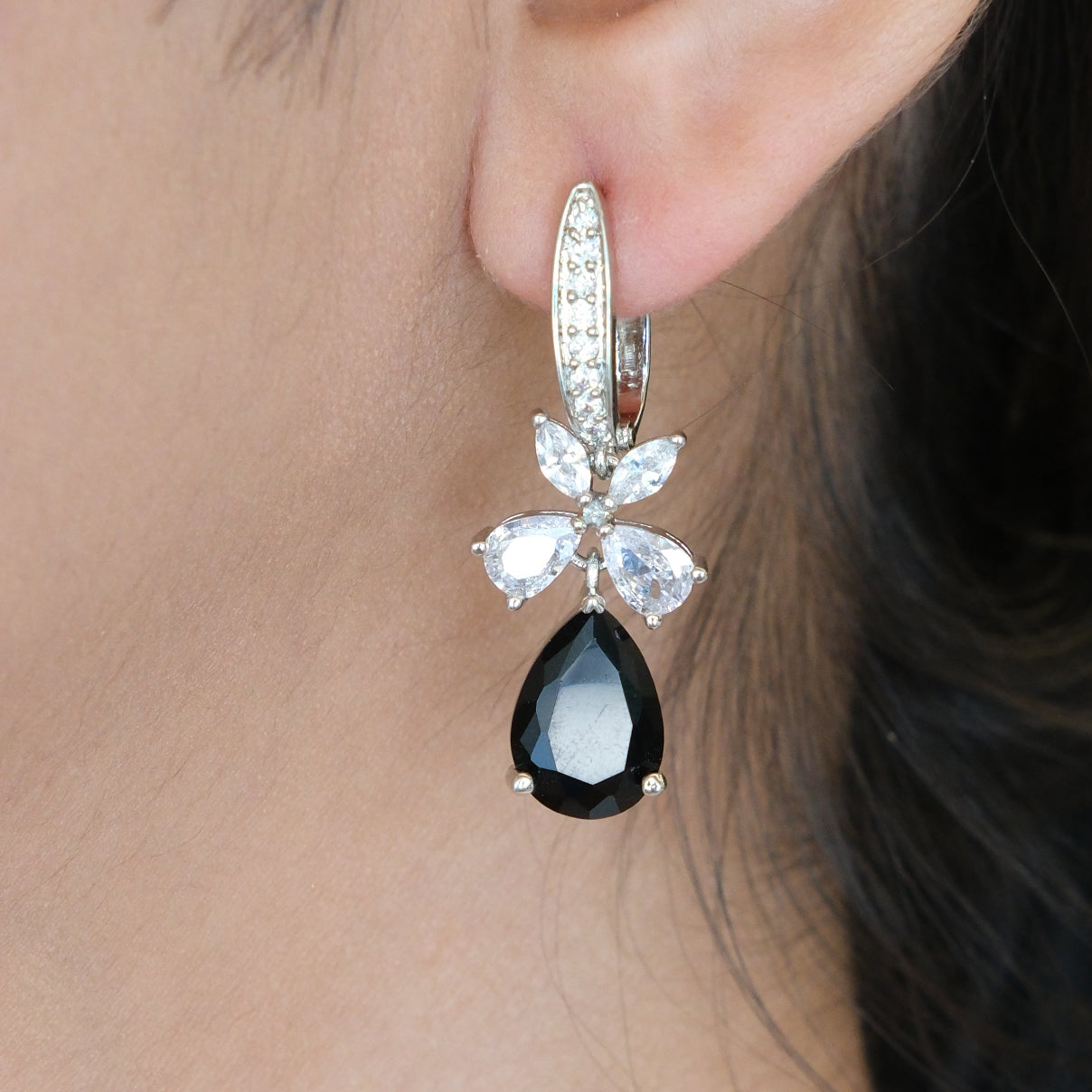 Earring with black teardrop gemstone and clear stones worn by a MODEL.