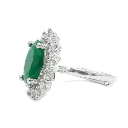 A silver-tone ring featuring a marquise-cut green emerald gemstone surrounded by small clear stones, shown on a plain white background.