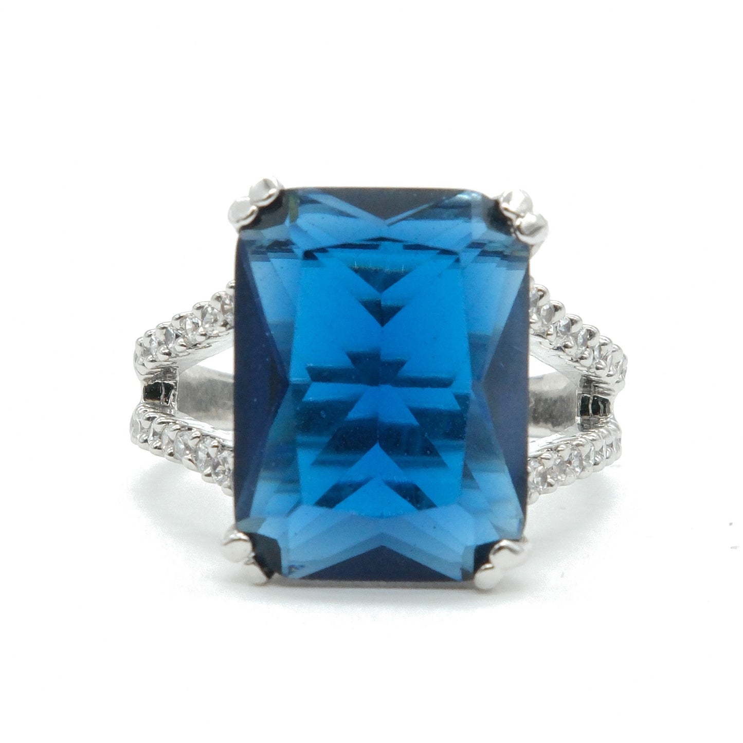 A rectangular blue gemstone ring with a silver-toned band accented by small clear stones, shown on a plain white background.