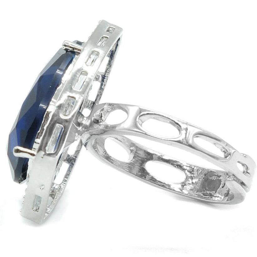 A silver ring featuring a large, faceted dark blue gemstone in a prong setting, with an openwork, filigree-style band, shown on a plain white background.