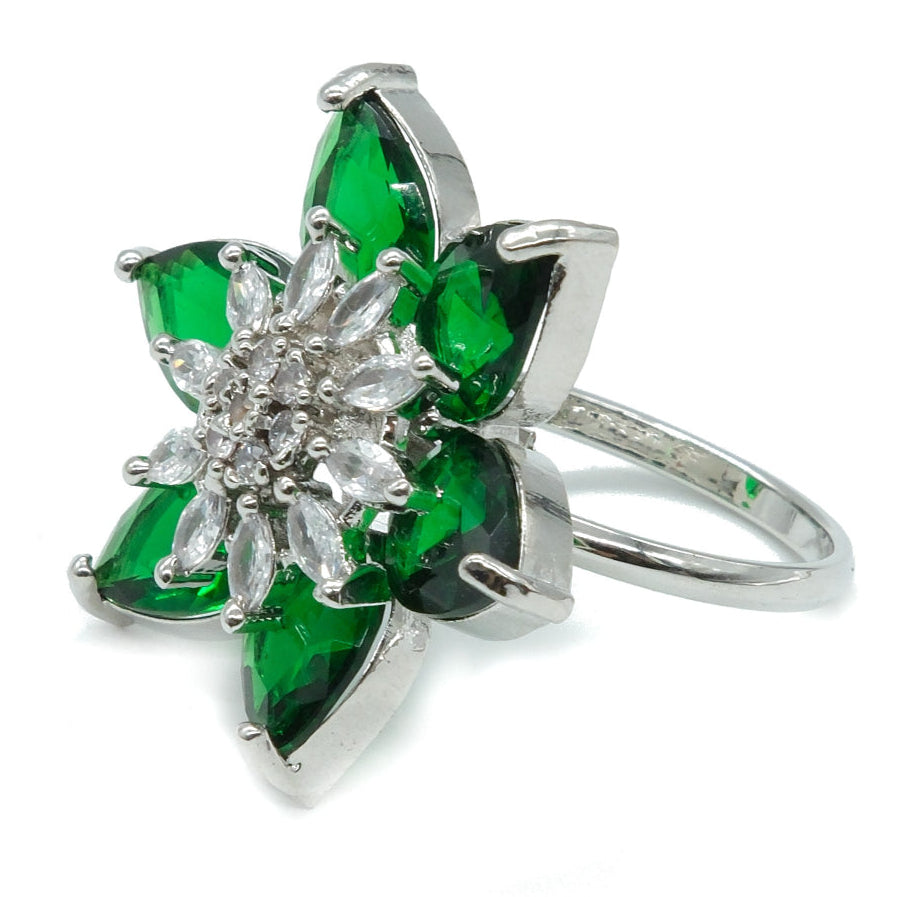 A silver-tone flower ring featuring six green marquise-cut stones surrounding a clear crystal center, set against a plain white background.