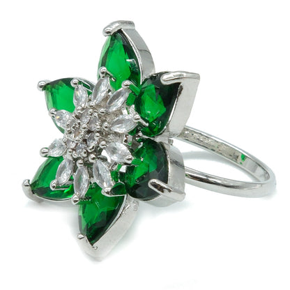 A silver-tone flower ring featuring six green marquise-cut stones surrounding a clear crystal center, set against a plain white background.