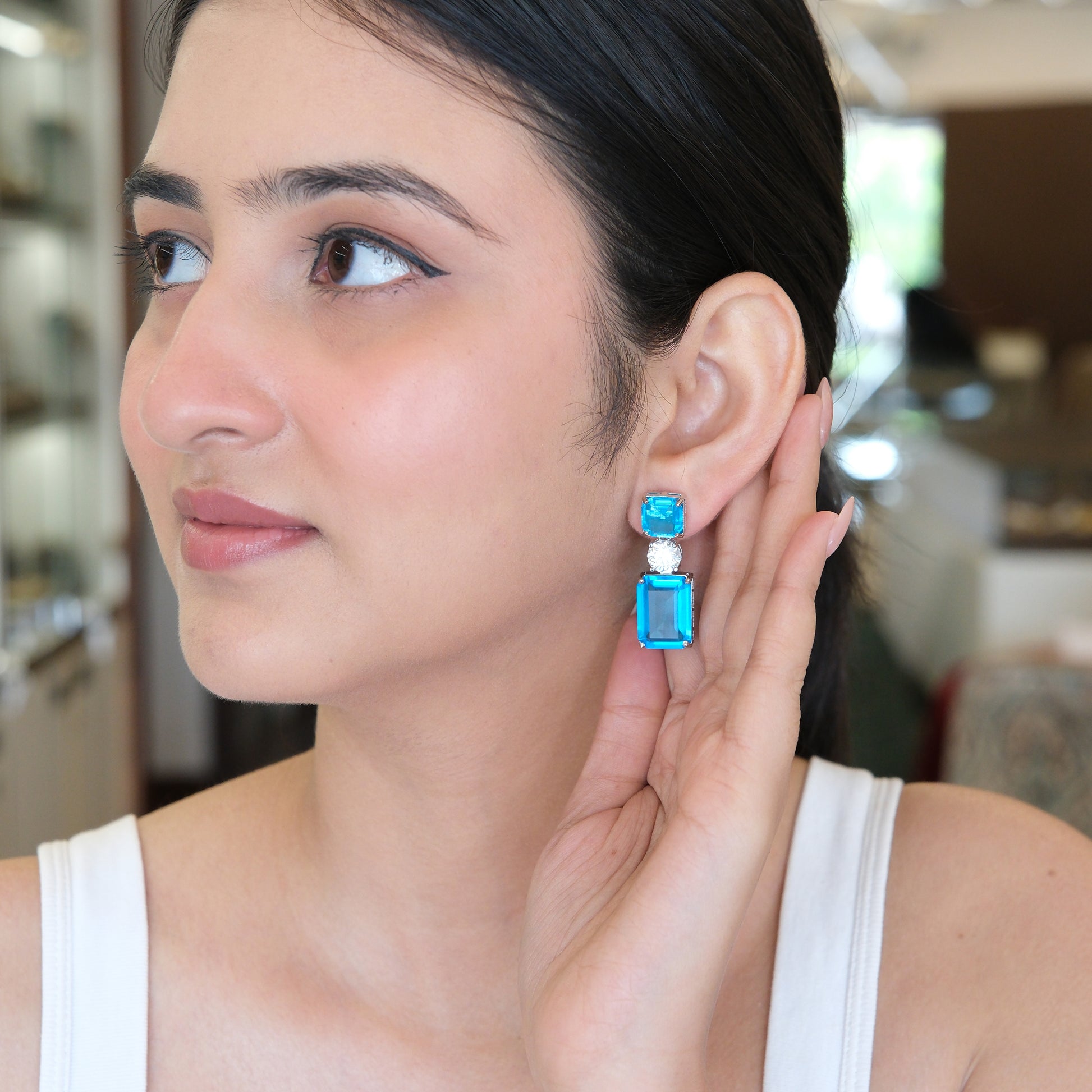 Model wearing blue gemstone drop earrings with crystal accents by Agulka