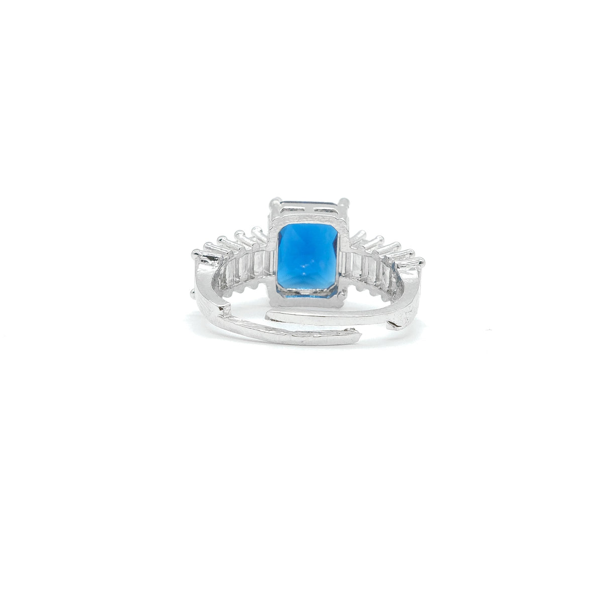 A silver ring featuring a rectangular bright blue gemstone in a prong setting, with small clear stones along the shoulders, shown on a plain white background.