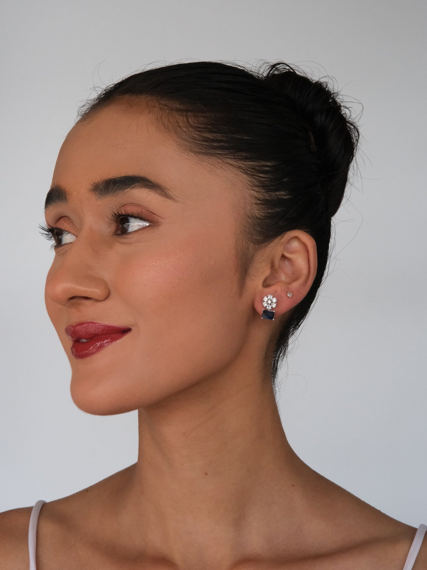 Model in a side pose wearing Blue American Diamond Drop Earrings, showcasing the elegant blue stones and sparkling American diamond drop design.
