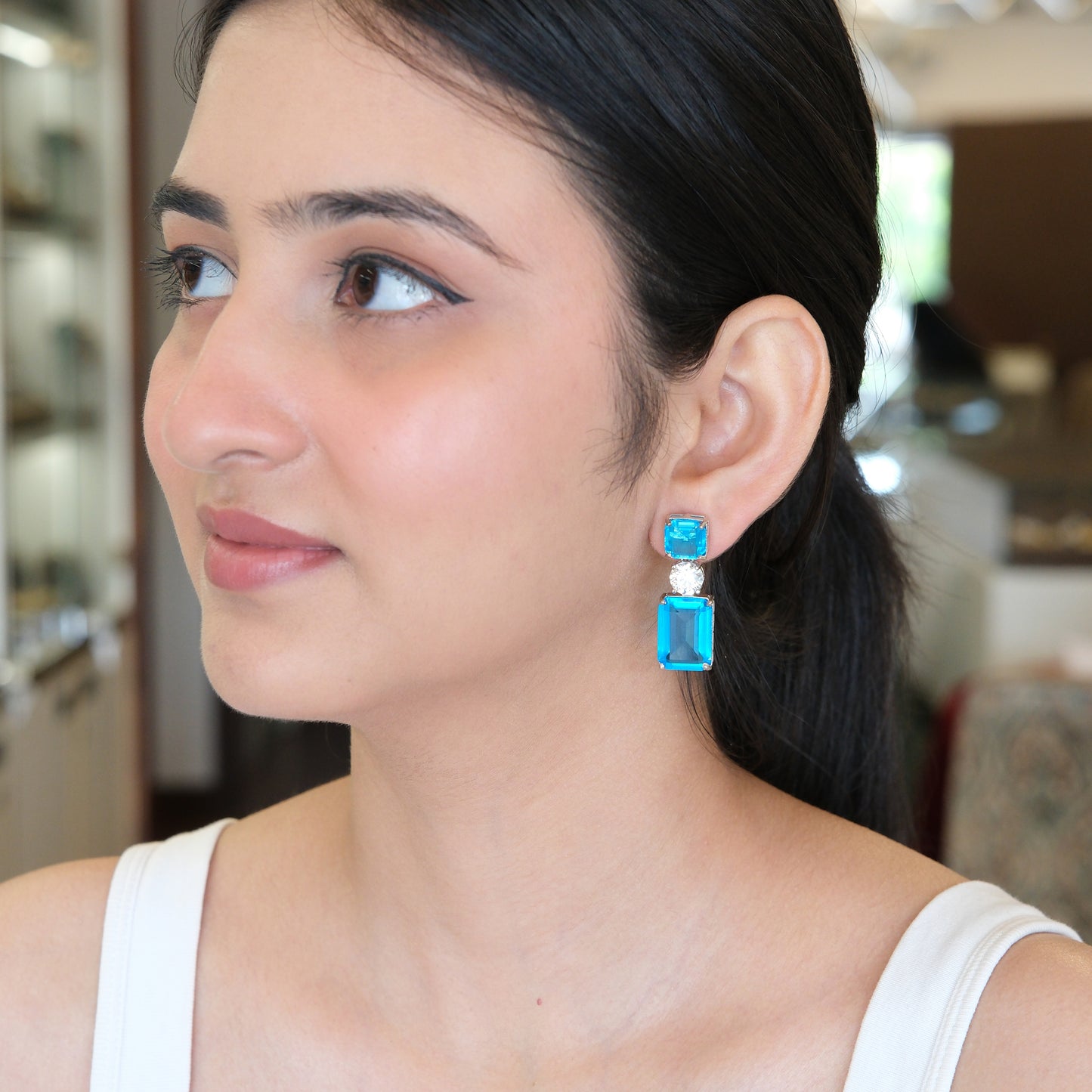 Model in a side pose wearing Blue Geometric Drop Earrings, showcasing the elegant geometric design and sparkling blue stones.