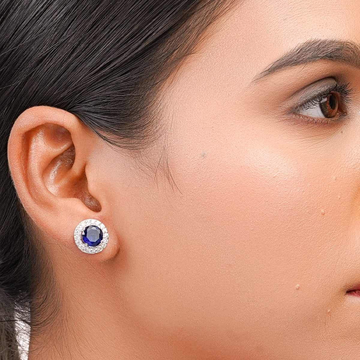 Model wearing one blue halo stud earring close-up