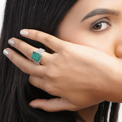 Close-up of model hand wearing green stone ring with side sparkle