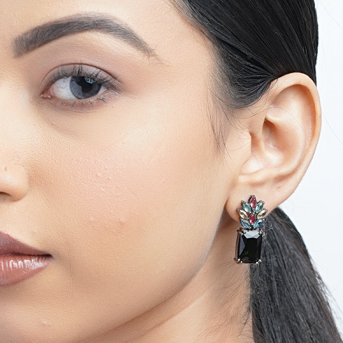 Model wearing small black earrings with colorful stones