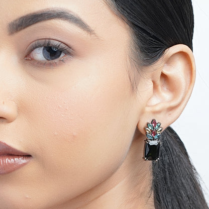 Model wearing small black earrings with colorful stones