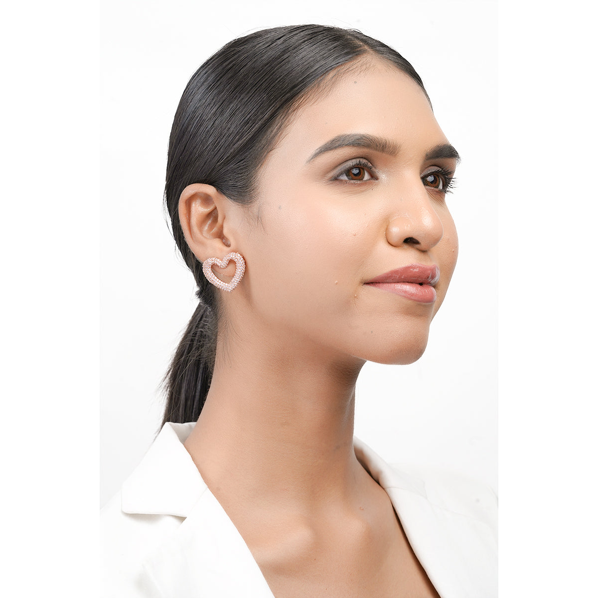Model with ponytail wearing pink heart CZ earrings in rose finish, smiling pose