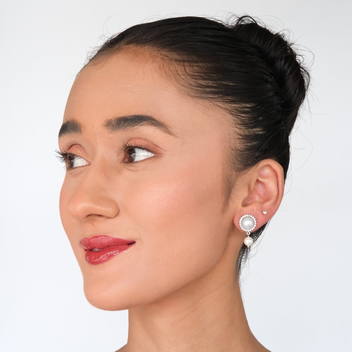 Model in a side view wearing Pearl Halo American Diamond Stud Earrings, showcasing the elegant pearl halo design and sparkling American diamonds.
