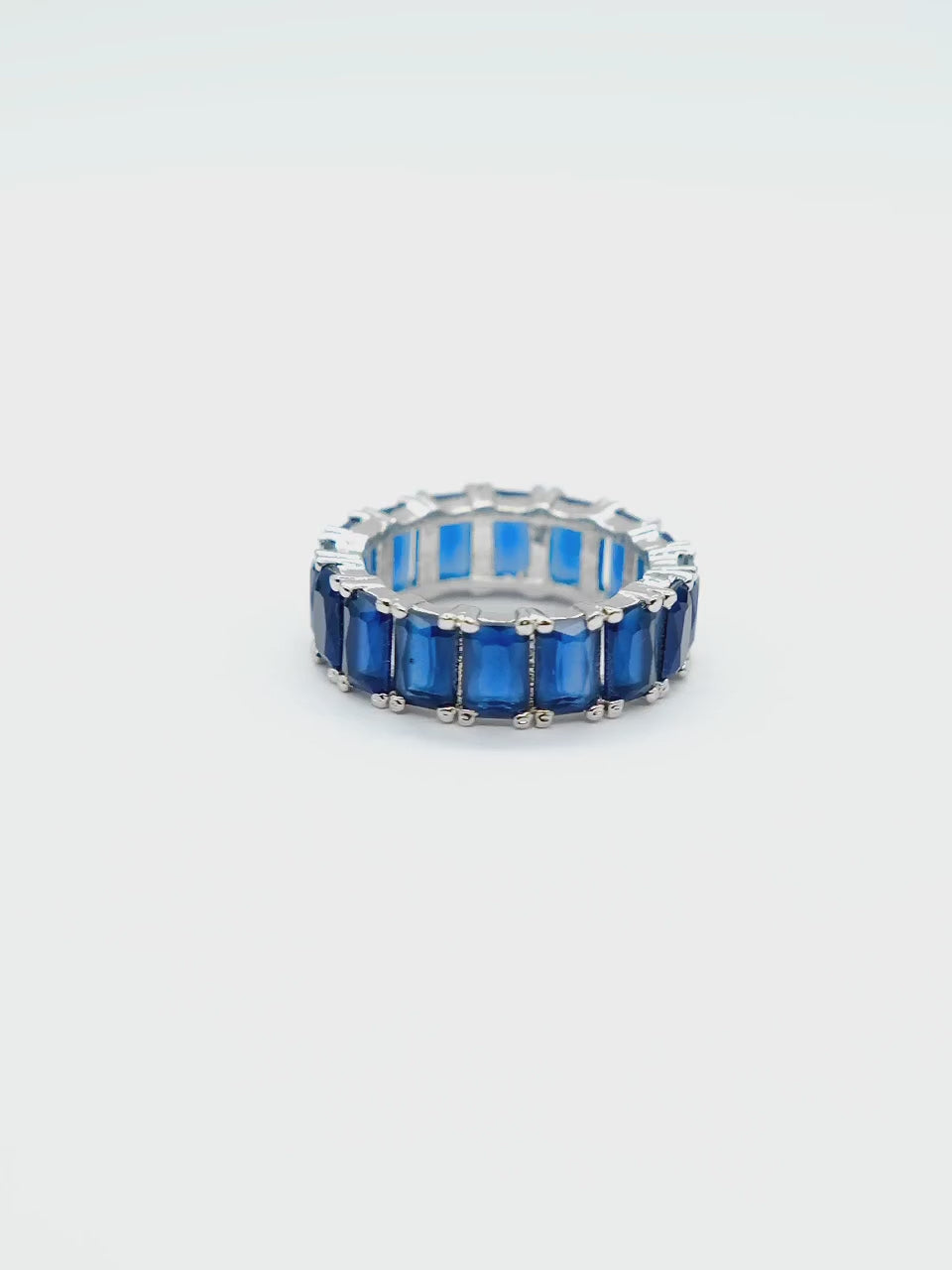 Close-up product video of the Blue Baguette Eternity Ring on a white background, showcasing the sparkling blue baguette stones and elegant eternity band design.