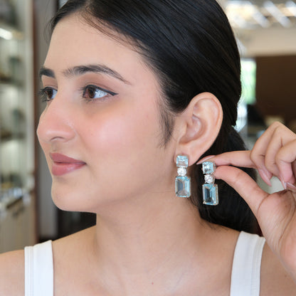 Model wearing Sky Blue Geometric Drop Earrings in a side view, highlighting the elegant geometric drop design and sparkling sky blue stones.